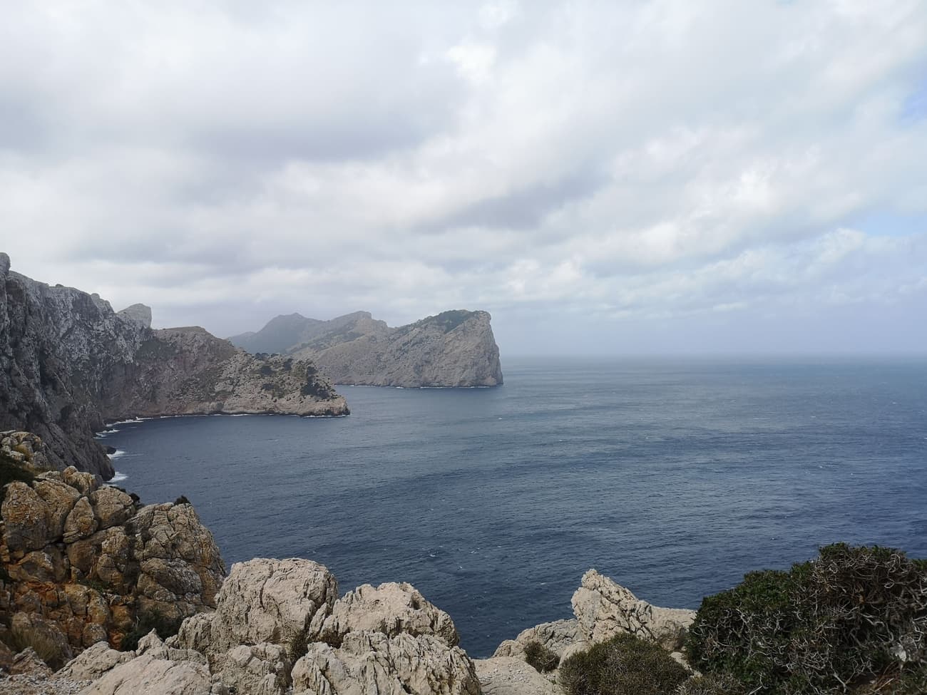 The limestone headland of Cap Formentor dropping into a grey-blue sea under heavy overcast.
