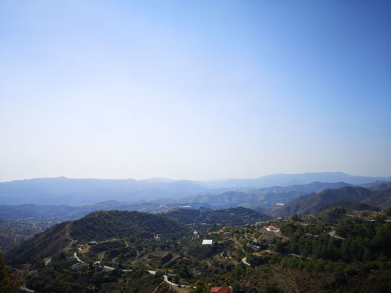 Hazy view across the Cypriot foothills, villages and winding roads spread over ridge after ridge.