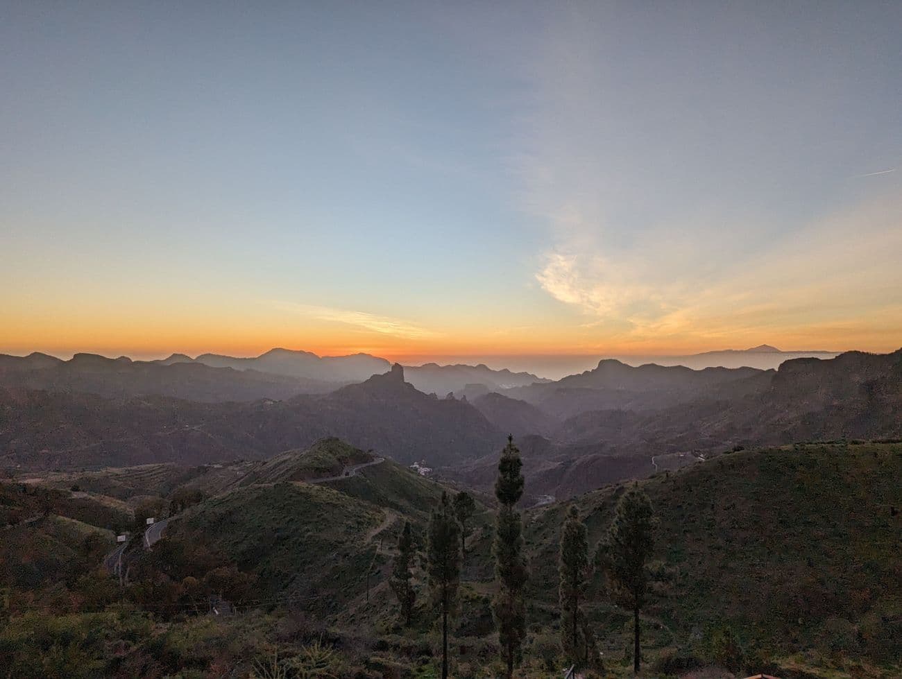 Sunset over the ridges of central Gran Canaria, Roque Bentayga in silhouette and Teide on the horizon beyond the sea.